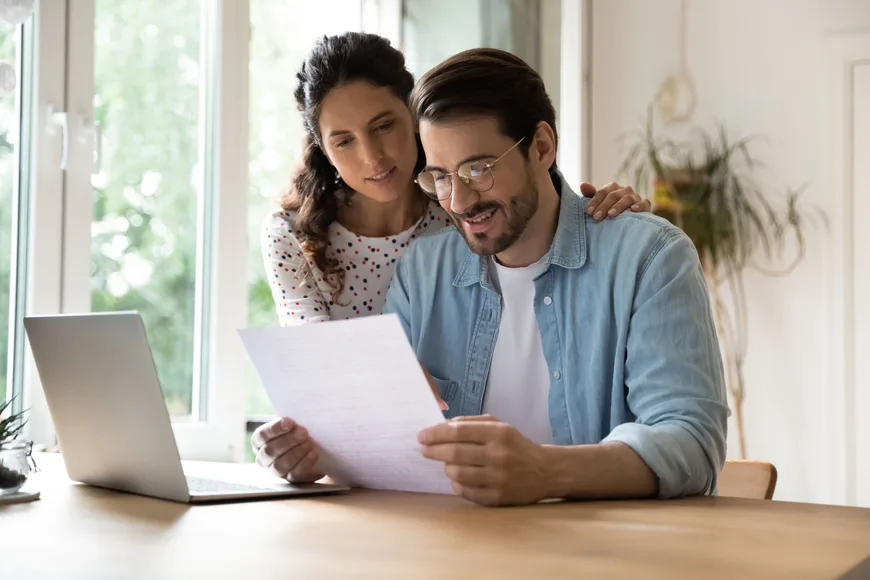 A couple is sitting at a table looking at a document together.