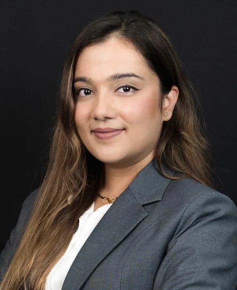 Jesica Dahal Professional Headshot Jesica Dahal in a business suit poses for a headshot against a dark background.