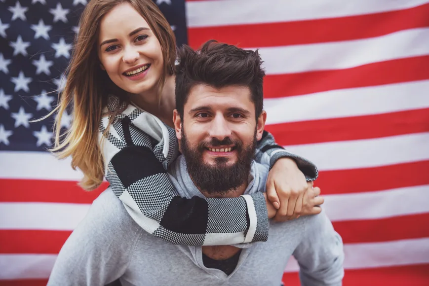 us person with his non resident alien spouse wife infront of us national flag